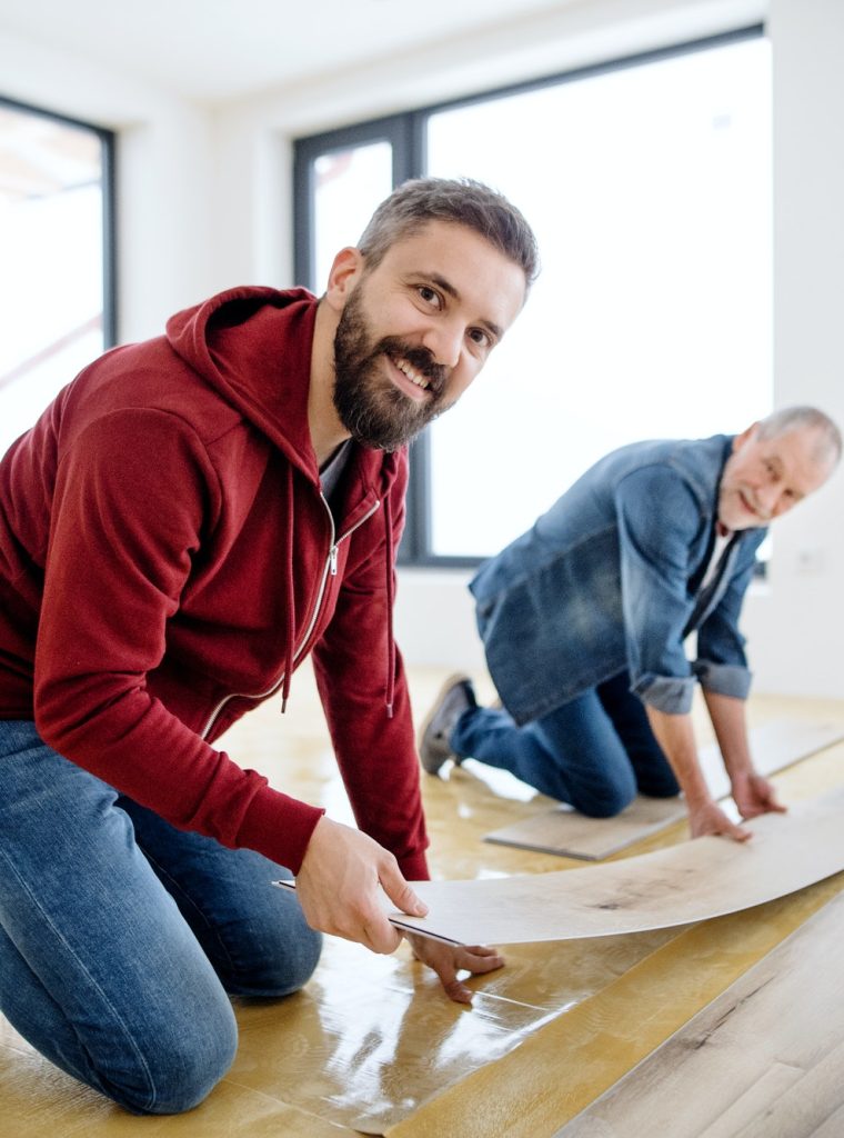 a-mature-man-with-his-senior-father-laying-vinyl-flooring-a-new-home-concept-.jpg